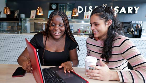 Two students study happily on a laptop together