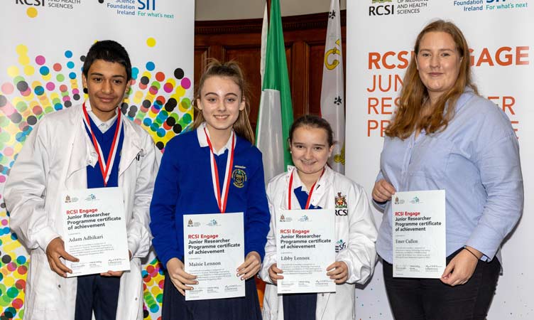 Three school children and one adult pose with certificates