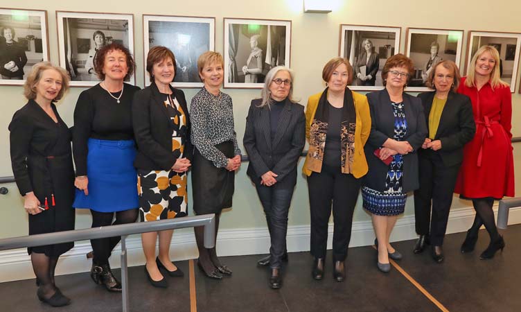Amelia Stein poses with other women with their portraits