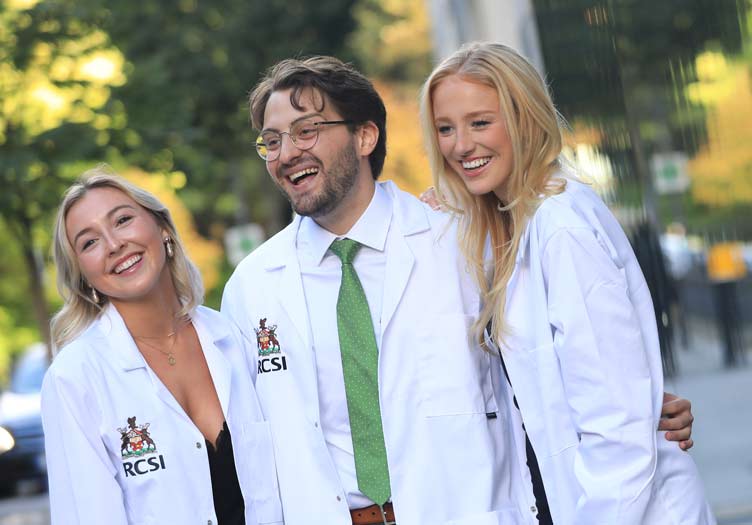 Happy students in white coats celebrate on a road