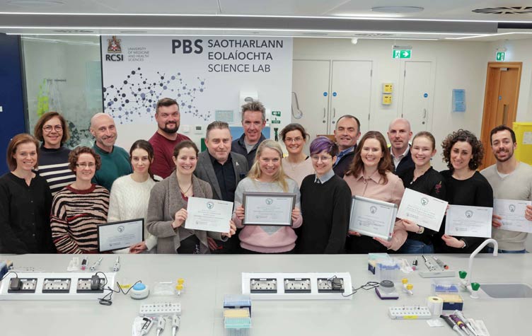 Large group of people hold aloft certificates