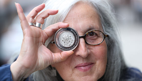 Award winner holds coin to eye