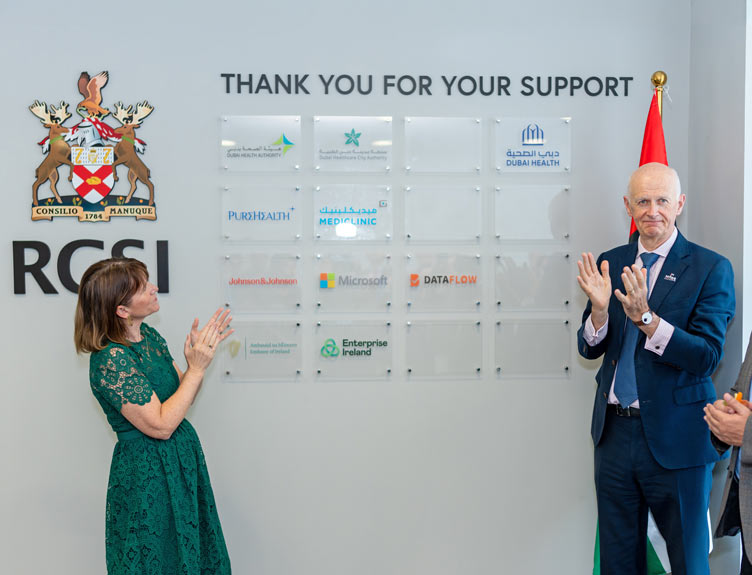 Two individuals clap in front of signage