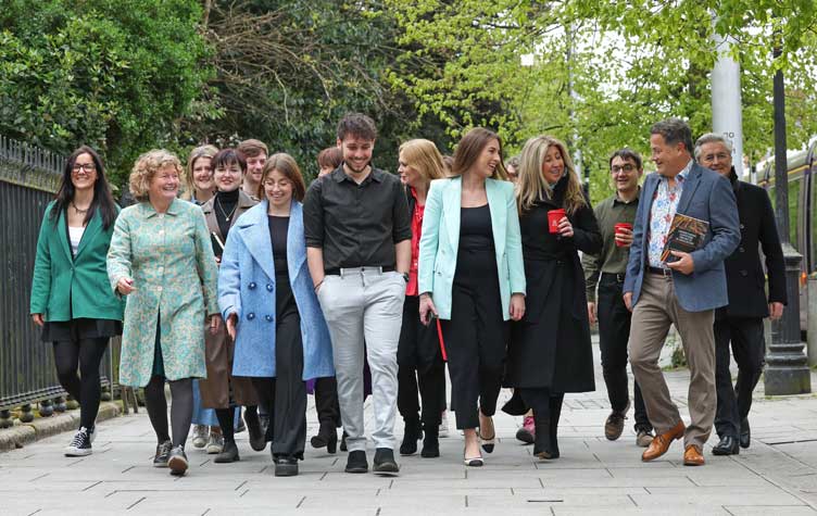 Happy staff members walk along leafy sidewalk