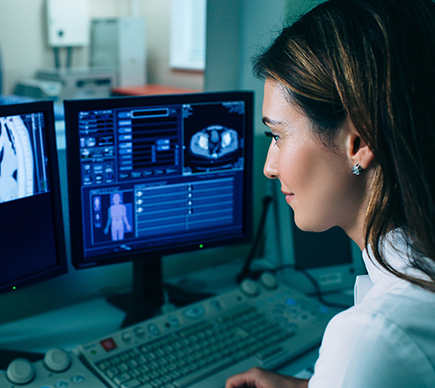 A female medical professional views a scan on a computer screen.