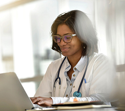 A doctor working at a laptop.