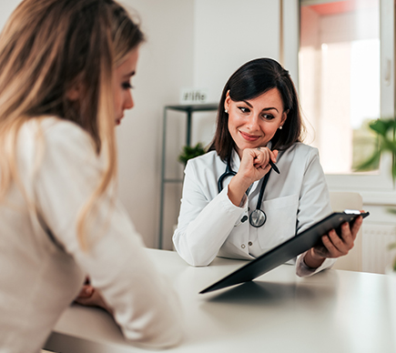 A doctor and colleague looking at information on a clipboard.