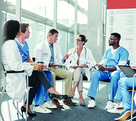 A group of seven medical professionals sitting in a circle and conferring.