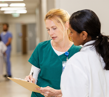 Two medical professionals conferring in a corridor.