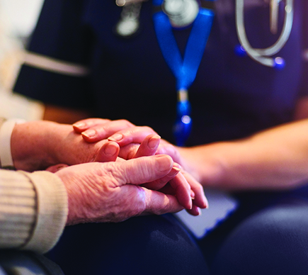 A nurse holding a bereaved person's hands.