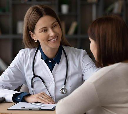 A medical professional coaching a patient at a desk.