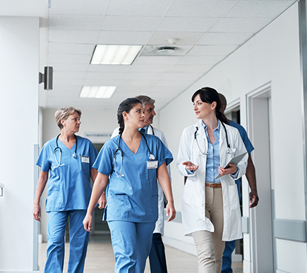 A group of doctors and nurses in a hospital corridor.