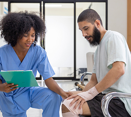 A nurse assists a man with a knee injury.