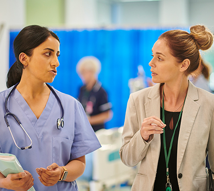 Two medical professionals in conversation in a hospital setting.