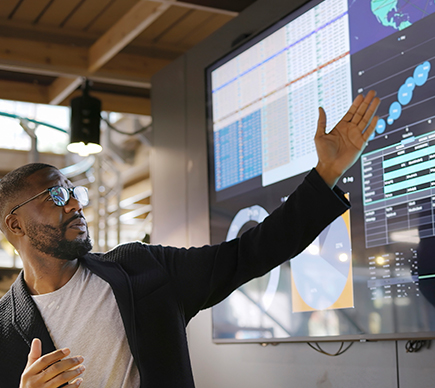 A man presenting data at a big screen.