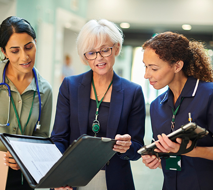 Three medical professionals discussing hard-copy and digital information.