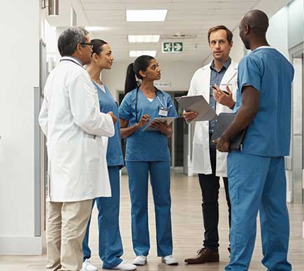 A group of medical professionals conferring in a hospital corridor.