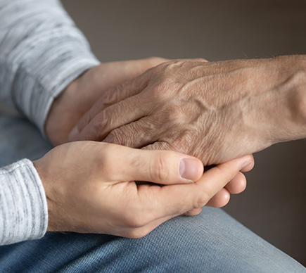 A medical professional holding the hand of an elderly patient.