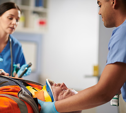 Two medics attach a neck support to a patient on a stretcher.