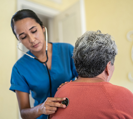 A female nurse with a stethoscope examines a patient.