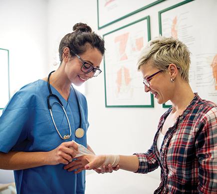 A female nurse dressing a patient's wrist injury.