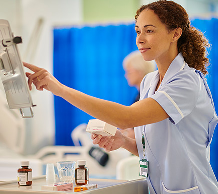 A nurse at a touchscreen workstation.